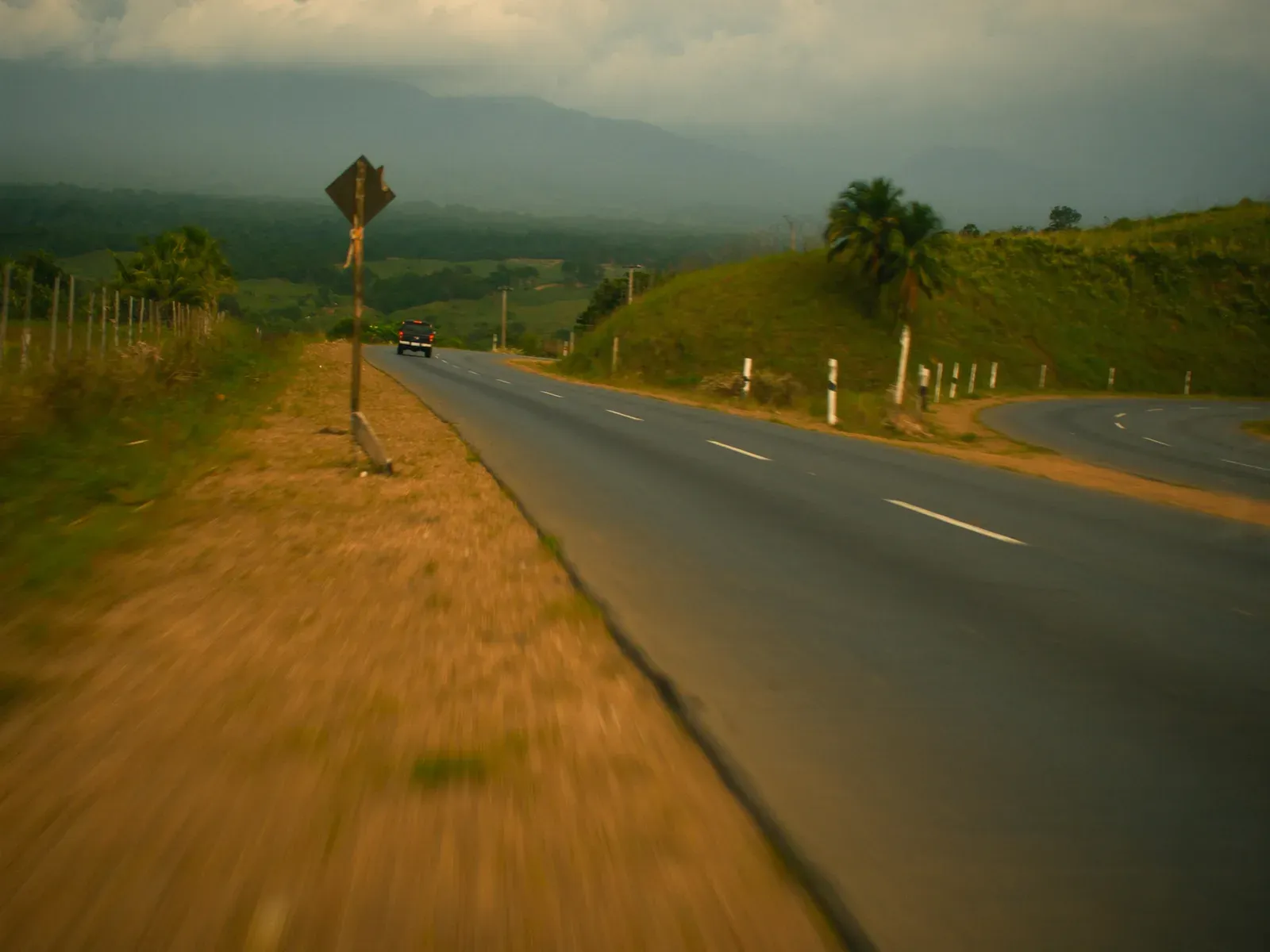 A two-lane road curving between green hills in Panama's interior