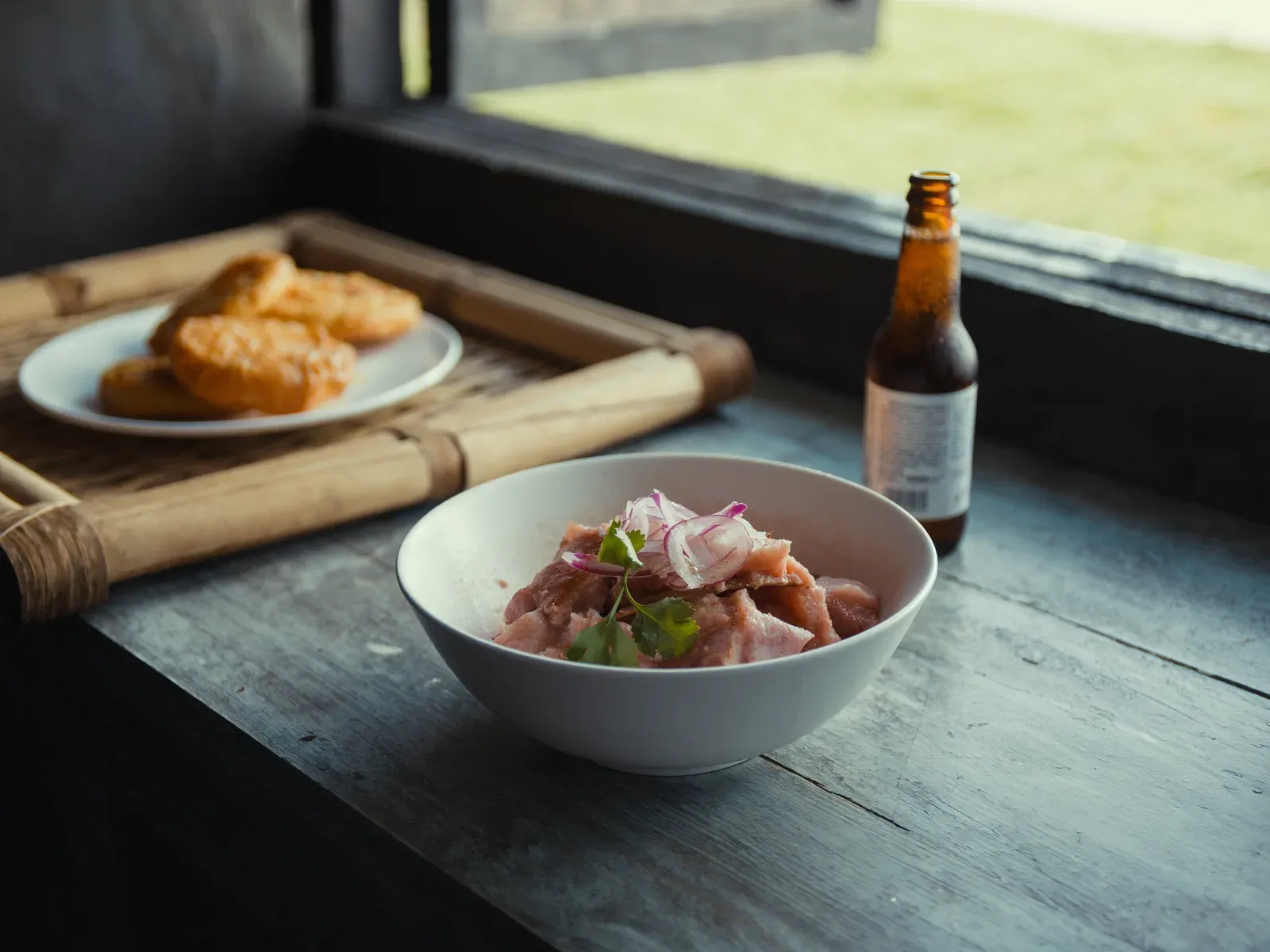 A bowl of fresh corvina ceviche with patacones on a wooden table